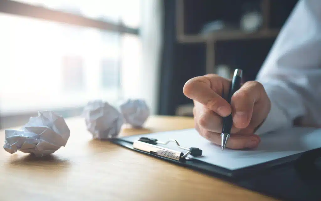 Businessman writing on the table with paper balls resume mistakes